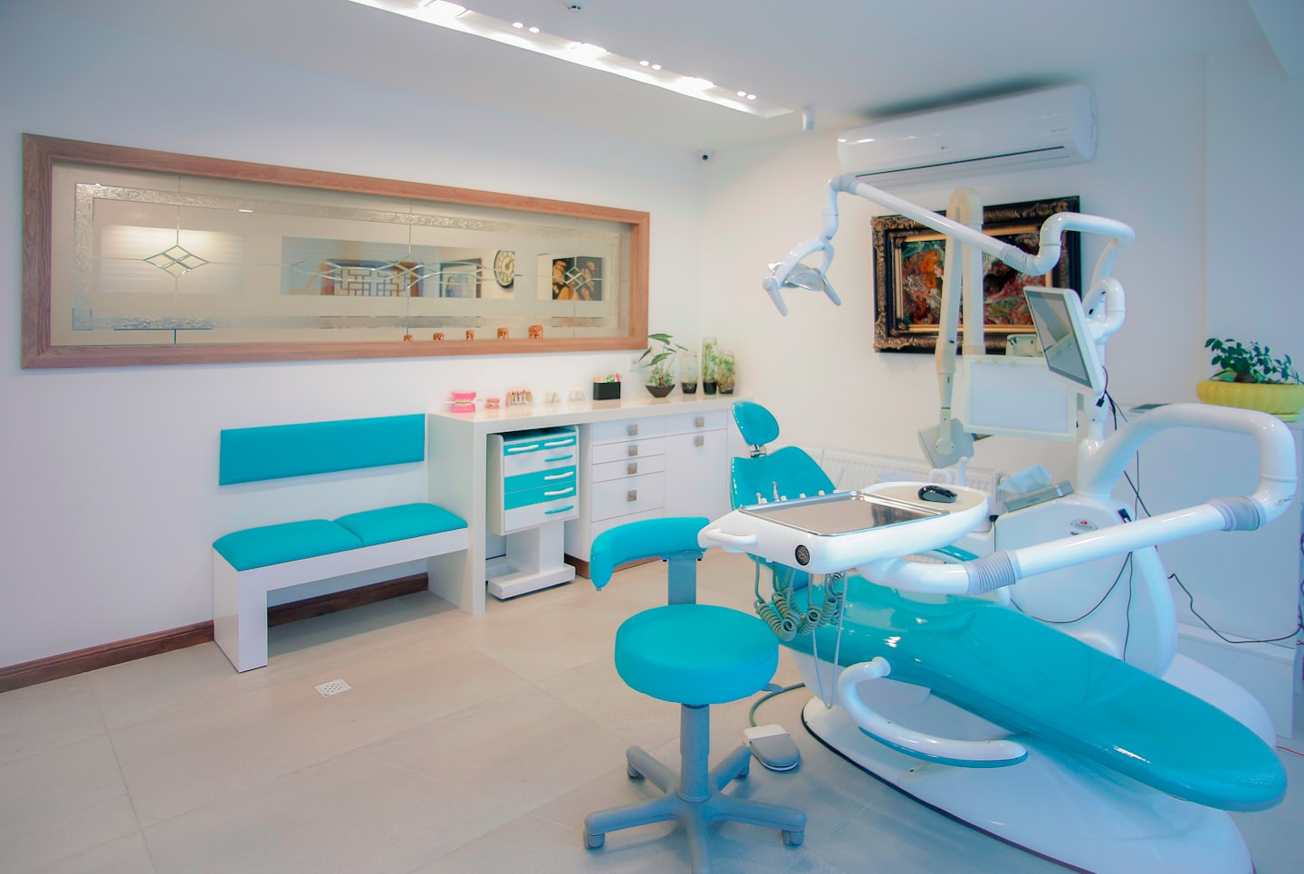Moderna clinica dentistica con poltrona turchese e panca d'attesa.